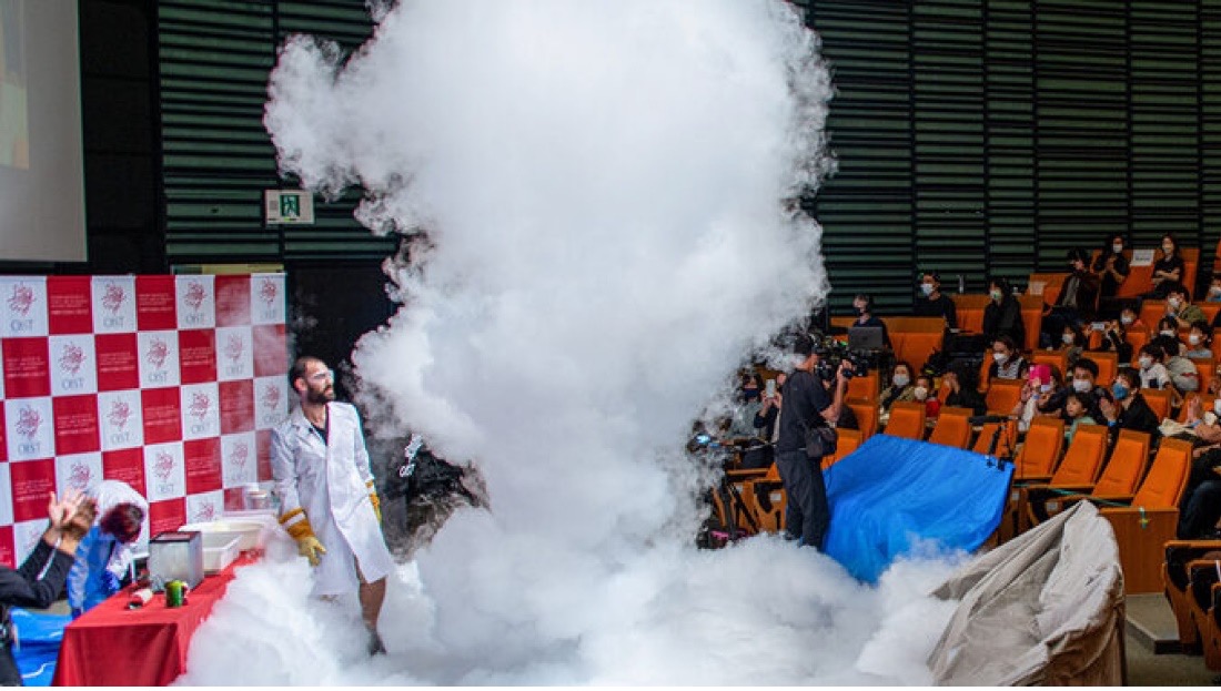 Scientist in white lab coat making an instant cloud on stage