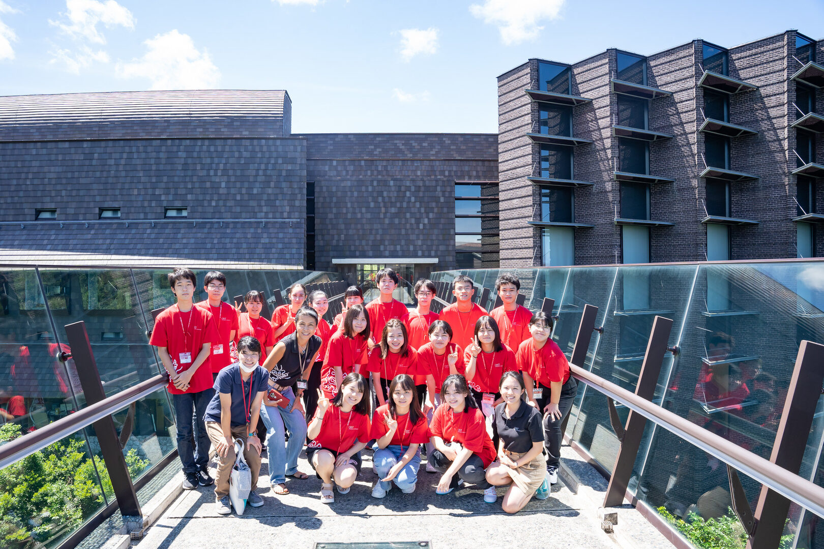 OIST staff with high school students in red shirts on the open sky walk